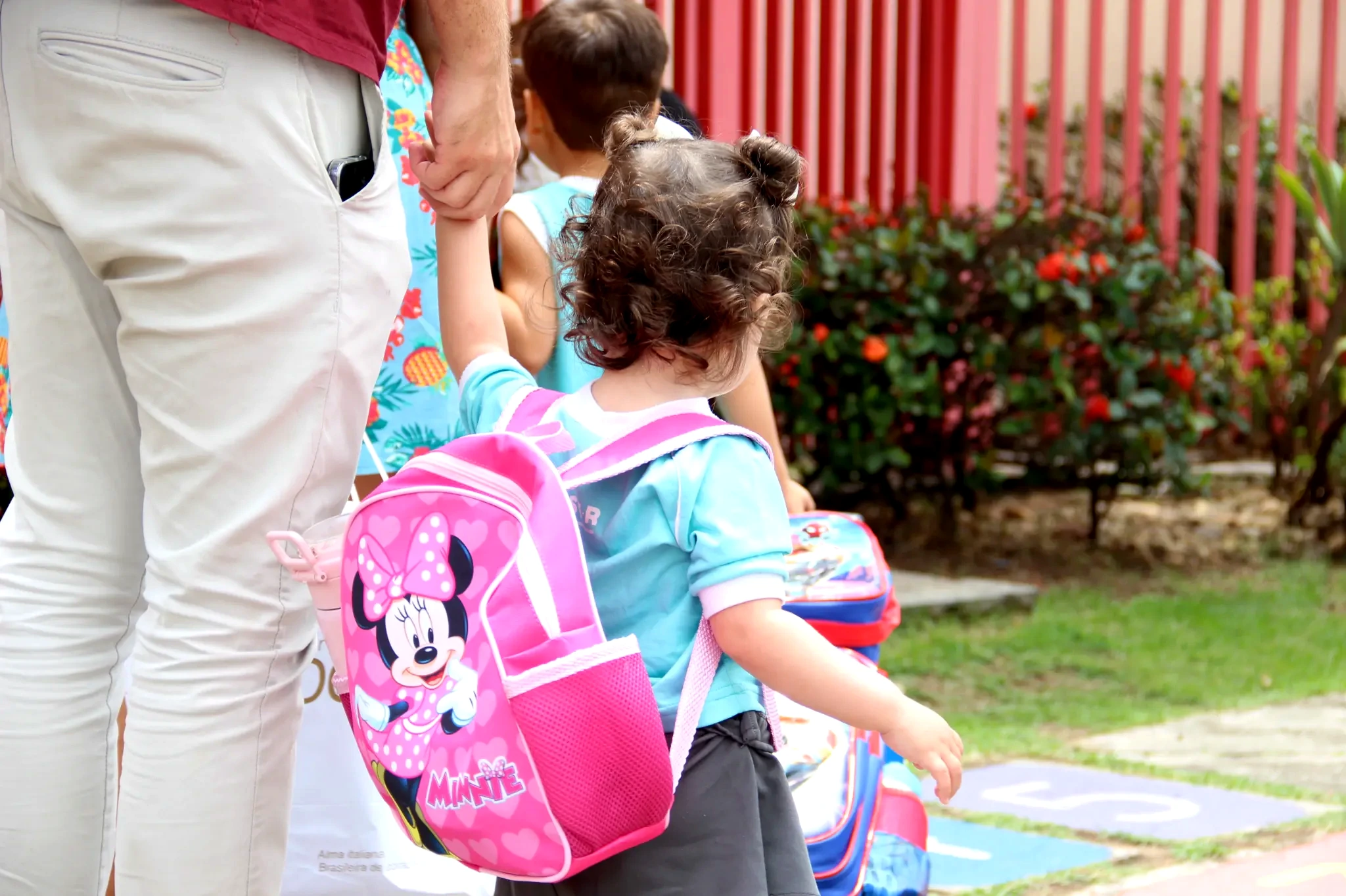 Criança chegando à escola acompanhada por um responsável